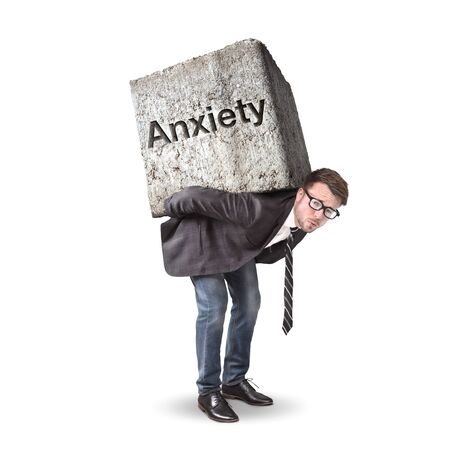 Man burdened by a heavy stone labeled with Anxietyの写真素材