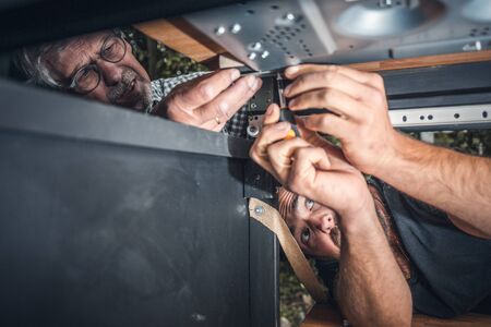 Two men installing a gas stove into a caravanの写真素材