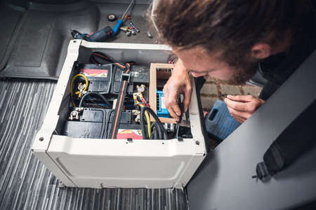 Man inside a van using heat shrink tubing on an electrical cable