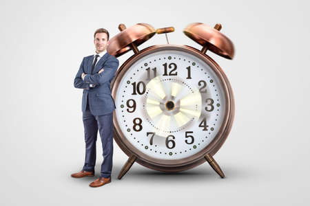 Businessman standing next to an oversized clock with spinning hands