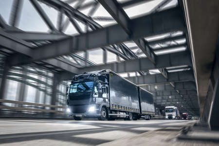 Several trucks driving over a bridge in an industrial areaの写真素材