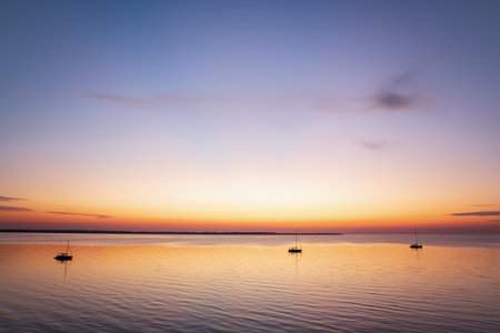 Boats anchored in a peaceful bay after sunset at the Baltic Seaの写真素材