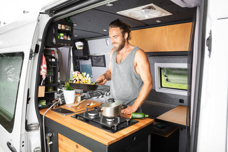 Smiling man cooking inside his camper vanの写真素材