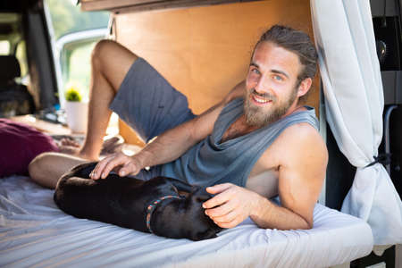 Man and his dog lying inside a camper vanの写真素材