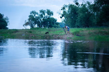 Angler setting up multiple rods for carp fishing on a river bankの写真素材