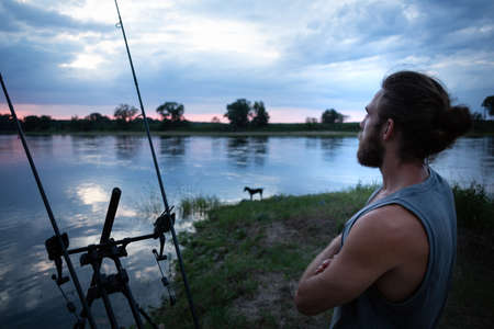 Angler waiting on a river bank at twilightの写真素材