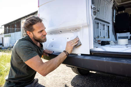 Man sanding the rear door of a van by handの写真素材