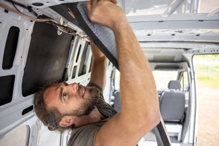 Man attaches thermal insulation on the inside of a vanの写真素材