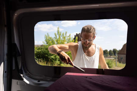 Man using a file to deburr a window opening in a camper vanの写真素材