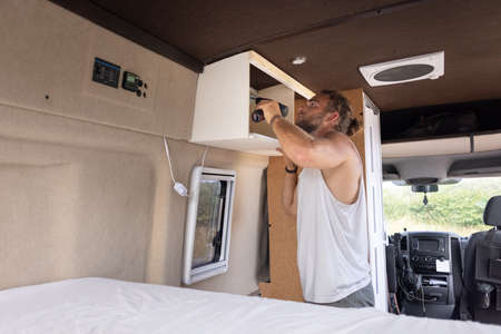 Man installing a small cupboard into a caravanの写真素材