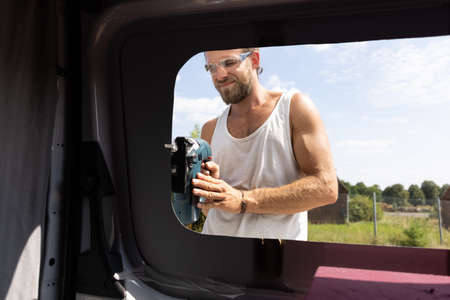 Man cuts a window into the side door of a vanの写真素材