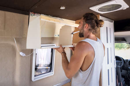 Man constructing a small cupboard inside a caravanの写真素材