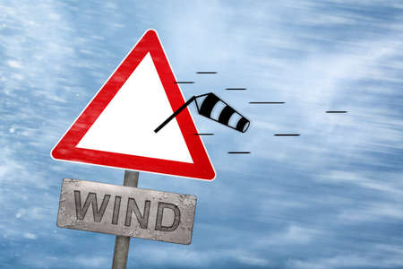 Wind warning sign getting blown away by a stormの写真素材