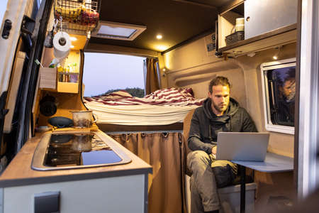 Man using a laptop computer inside his camper vanの写真素材