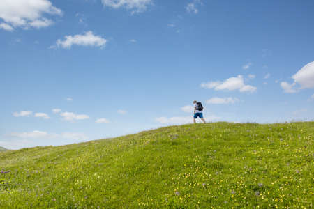 Hiker walking along a lush green hillの写真素材