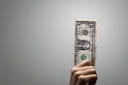 Single one dollar bill held by a hand
