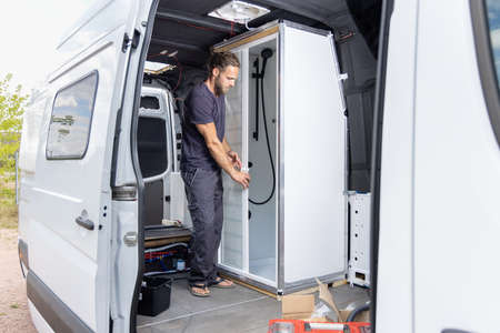 Man installing a shower room inside a camper vanの写真素材