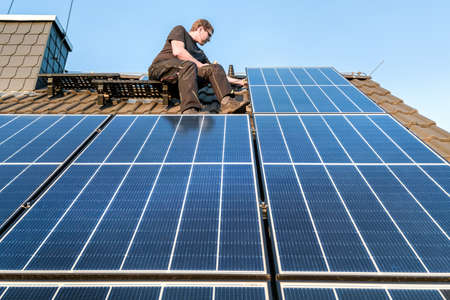 Person next to solar panels on a rooftopの写真素材