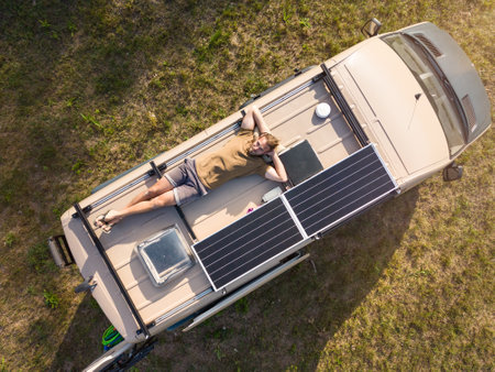 Aerial view of a man lying on the roof of a camper vanの写真素材