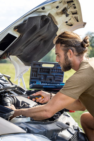 Man working inside the engine compartment of a van outdoorsの写真素材