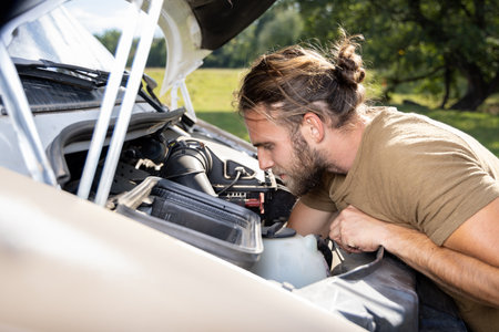 Man working inside the engine compartment of a van outdoorsの写真素材