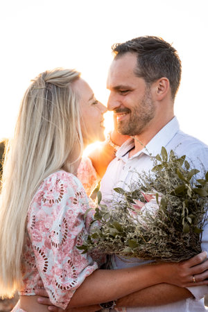 Portrait of a happy couple with a bouquet during a warm sunsetの写真素材