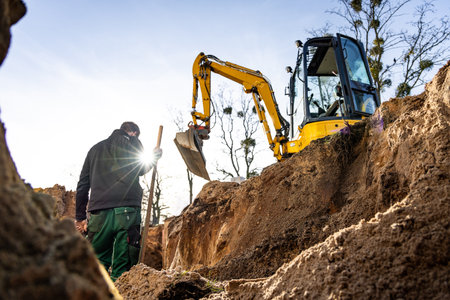 Excavation and earthwork at a construction site with a person and excavatorの写真素材