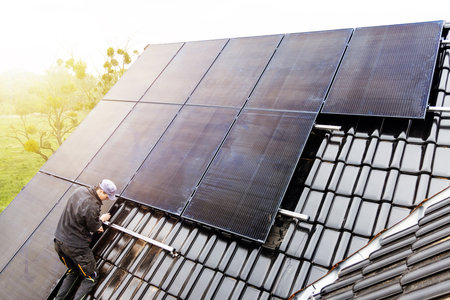 Technician installing solar panels on the roof of a houseの写真素材