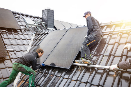 Tradesmen installing solar panels on the roof of a houseの写真素材
