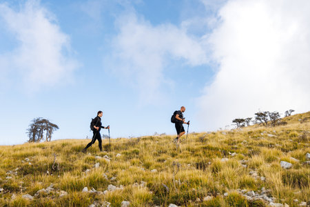 Ascending a Grassy Slope: Two People Hiking in Southern Albaniaの写真素材