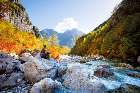 Man Sitting on a Rock Near a River in the Colorful Albanian Alpsの写真素材