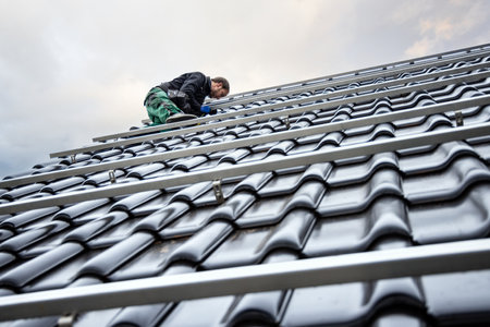 Technician on the Roof of a House Setting Up Mounting Structures for Solar Panelsの写真素材