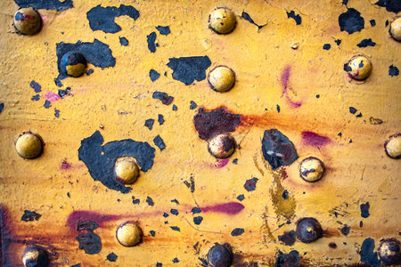 Old Rusty Metal Surface with Bolts and Peeling Yellow Paint