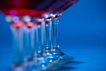 Detail of glasses filled with red wine over blue background の写真素材