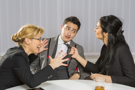 Two angry businesswomen harassing their guilty business partner in the office.の写真素材