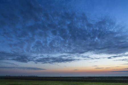 Sunrise with cloudy sky over green meadows in Comana Natural Park, Romania