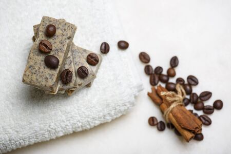 Stack of handmade coffee and cinnamon flavored soap bars on white towel.の写真素材