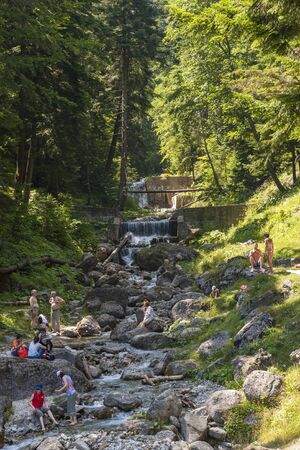 BUSTENI, ROMANIA - JULY 25: Tourists relax and tan by a mountain creek on July 25, 2009 in Busteni, Romania. Busteni resort is one of the most popular mountain resorts at the base of Bucegi Mountains.のeditorial素材