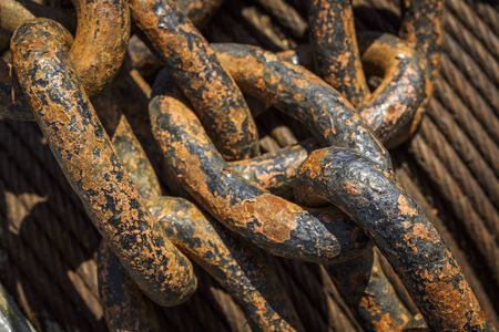 Close view of large rusted anchor chains over a pile of rusted iron cables. Shallow depth of field.の写真素材