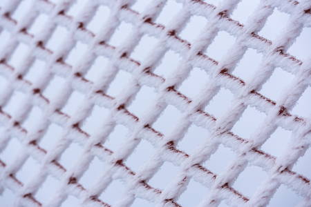 Close view of protection net, fence covered by snow and hoarfrost. Shallow depth of field.の写真素材