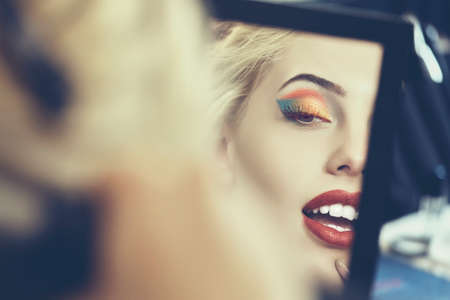 Detail of beautiful sensual woman face in a mirror. Beauty makeup and cosmetics treatment. Shallow depth of field and mate color grading.の写真素材