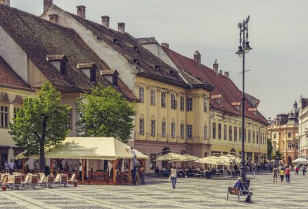 SIBIU, ROMANIA - 06 MAY, 2015: Unidentified people stroll along the promenade on a sunny day in the Great Square, the largest square in the upper town and an architectural monument by UNESCO.のeditorial素材