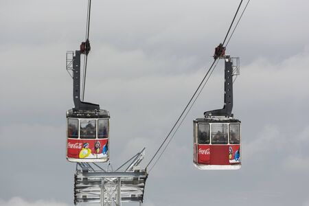 POIANA BRASOV, ROMANIA - NOVEMBER 23, 2014: Two cable car cabins with Coca-Cola advertisement transport tourists from Poiana Brasov resort to Postavaru peak and ski slopes on a overcast winter day.のeditorial素材