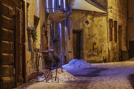 BRASOV, ROMANIA - 01 DECEMBER, 2014: Wintry night view of an empty backstreet with vintage bike parking rack in the historic center of Brasov, the 7th largest city and the most visited in Romania.のeditorial素材