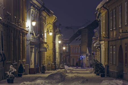 BRASOV, ROMANIA - 29 DECEMBER, 2014: Peaceful winter night urban view with snowy backstreet in the historic center of Brasov, the 7th largest city and most visited in Romania.のeditorial素材