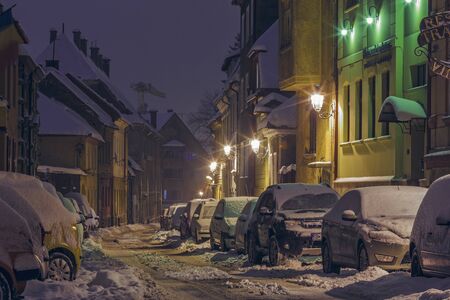 BRASOV, ROMANIA - 29 DECEMBER, 2014: Peaceful winter night scene with snowbound parked cars on a snowy backstreet in the historic center of Brasov, the 7th largest city and most visited in Romania.のeditorial素材