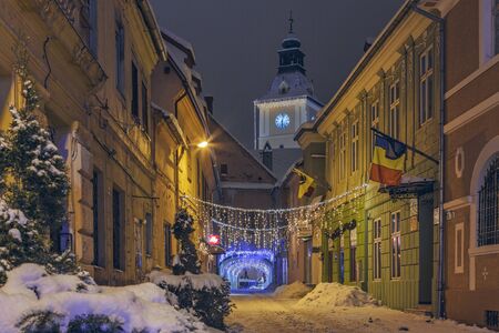 BRASOV, ROMANIA - 6 JANUARY, 2015: Wintry night scene of an empty snowy backstreet decorated with festive traditional Christmas lights in historic center of Brasov, the 7th largest city in Romania.のeditorial素材