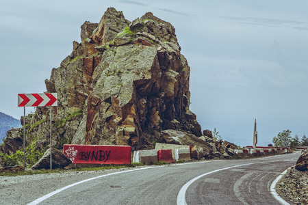 Roadside red and white triple chevron sign warning for dangerous road turn on sinuous Transfagarasan highway, Romania.の写真素材