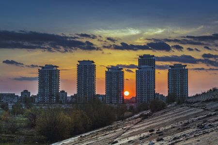 Idyllic scenery with setting sun behind modern residential skyscrapers near Vacaresti Lake dam, in south-eastern Bucharest, Romania. High rise apartment blocks, tower blocks, real estate development.の写真素材