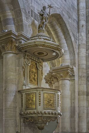 Alba Iulia, Romania - July 24, 2016: Stone pulpit with golden bass-reliefs inside Romano Catholic Cathedral of Alba Iulia. Archangel Michael statue holding a cross stands above the pulpit.のeditorial素材